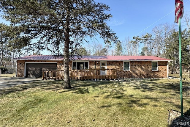 view of front of house featuring brick siding, a front yard, metal roof, driveway, and an attached garage