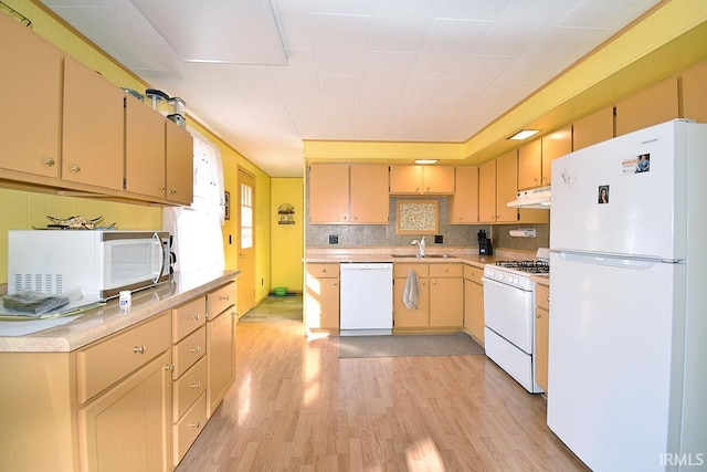 kitchen with white appliances, light wood finished floors, light countertops, and under cabinet range hood