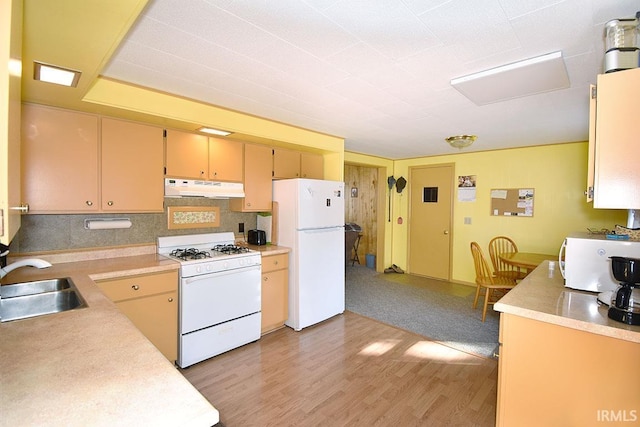 kitchen featuring under cabinet range hood, light countertops, light wood-style floors, white appliances, and a sink