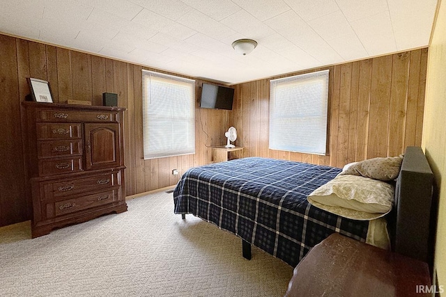 bedroom featuring wooden walls and carpet