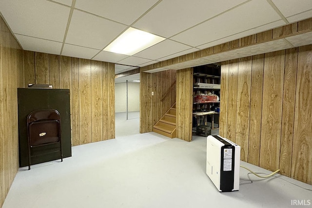 finished basement featuring stairway, wooden walls, and a paneled ceiling