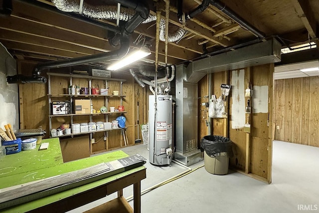 unfinished basement featuring gas water heater and wood walls