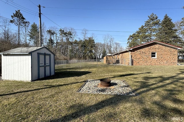 view of yard with a storage unit, an outdoor fire pit, an outbuilding, and fence