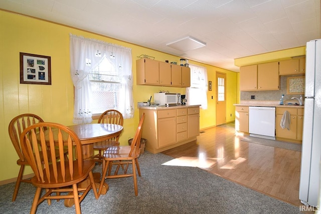 kitchen featuring a wealth of natural light, white appliances, light wood-type flooring, and light countertops