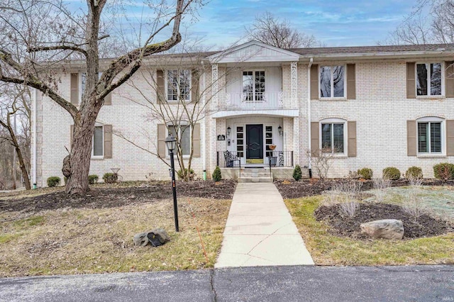 view of front of house with brick siding and a balcony