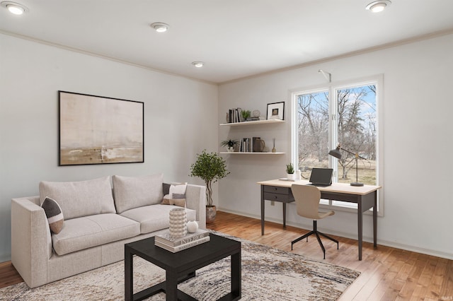 living area with baseboards, wood finished floors, and crown molding