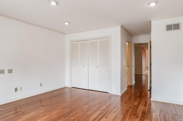 unfurnished bedroom with baseboards, wood finished floors, visible vents, and ornamental molding