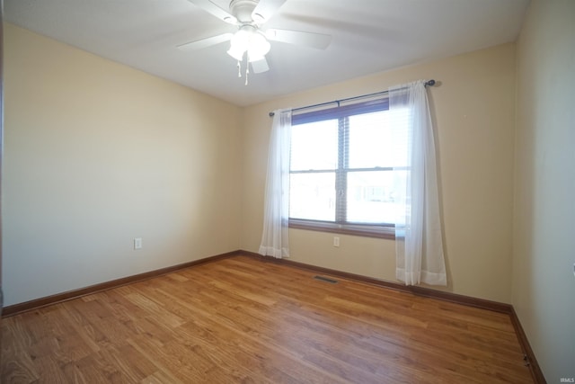 empty room featuring visible vents, light wood-style flooring, a ceiling fan, and baseboards