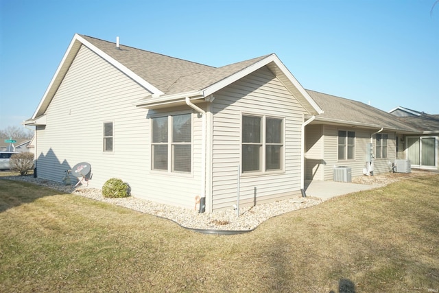 rear view of house with a patio area, central air condition unit, a lawn, and a shingled roof