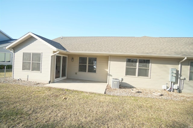 rear view of house featuring a patio, cooling unit, a yard, and a shingled roof