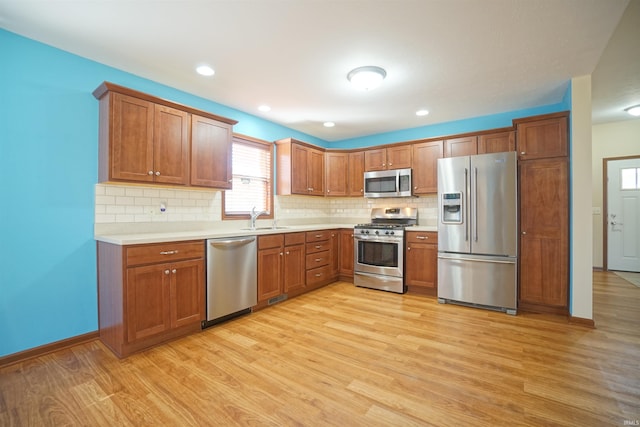 kitchen with a sink, stainless steel appliances, light wood-type flooring, and light countertops