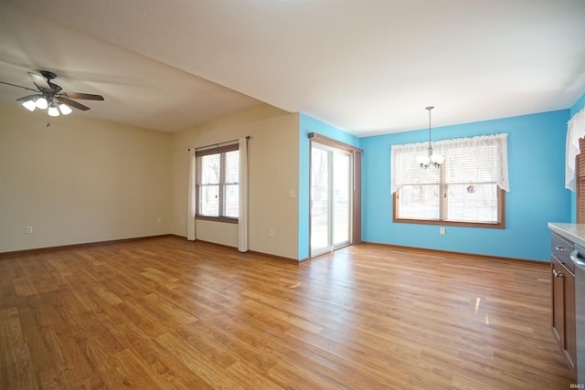 unfurnished living room featuring ceiling fan with notable chandelier, light wood-type flooring, and baseboards