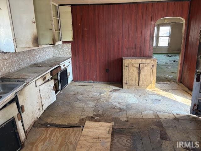 kitchen featuring arched walkways, backsplash, and a sink