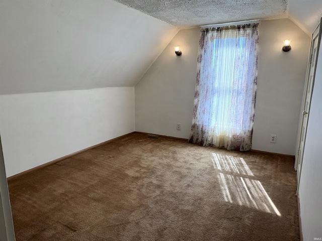 bonus room with a textured ceiling, lofted ceiling, and carpet