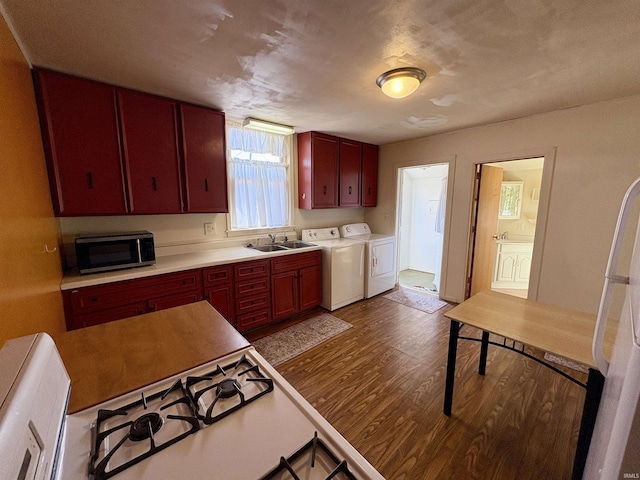 kitchen with dark wood finished floors, freestanding refrigerator, a sink, stainless steel microwave, and washing machine and dryer