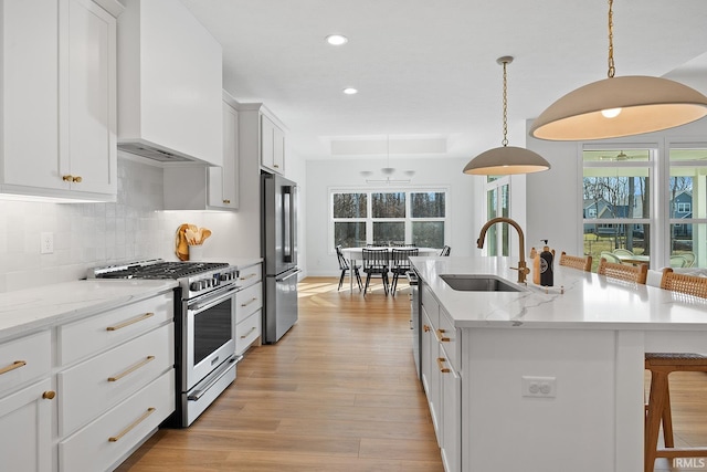 kitchen with premium range hood, a breakfast bar area, light wood-type flooring, appliances with stainless steel finishes, and a sink