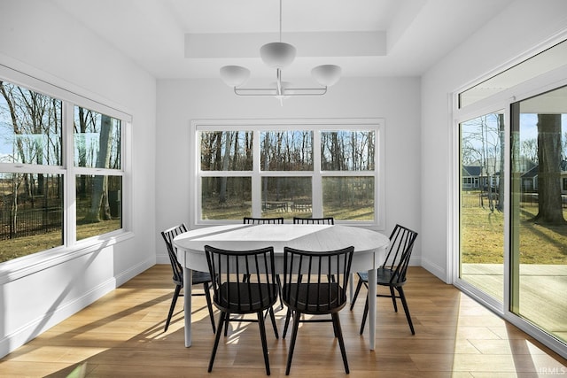 sunroom / solarium with a notable chandelier, a healthy amount of sunlight, and a raised ceiling