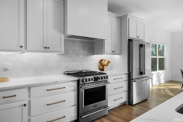 kitchen with tasteful backsplash, light stone countertops, dark wood-style floors, white cabinets, and stainless steel appliances