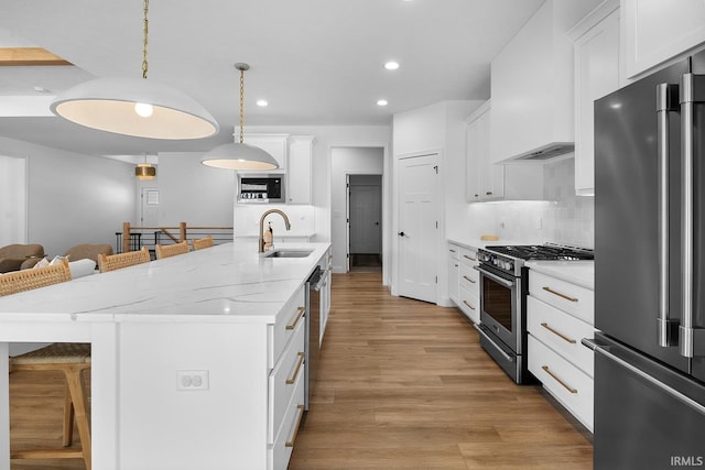 kitchen with a breakfast bar area, custom exhaust hood, a sink, stainless steel appliances, and white cabinetry