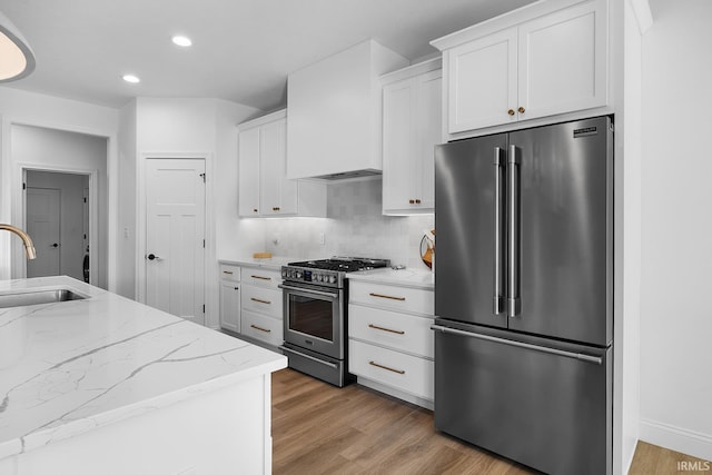 kitchen featuring a sink, backsplash, light wood-style floors, and appliances with stainless steel finishes