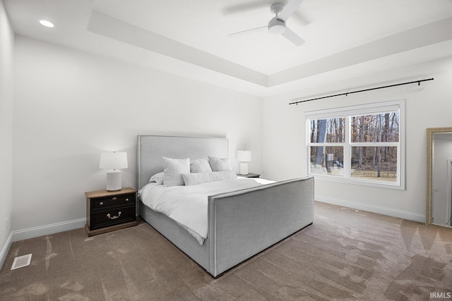 bedroom featuring baseboards, a raised ceiling, and carpet