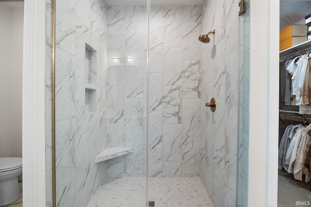 bathroom with a walk in closet, toilet, and a marble finish shower