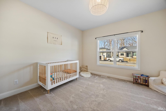 carpeted bedroom featuring a crib and baseboards