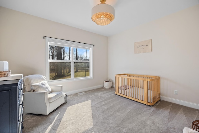 carpeted bedroom with baseboards and a nursery area