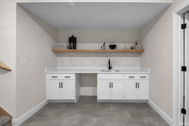 bar featuring tasteful backsplash, baseboards, and a sink