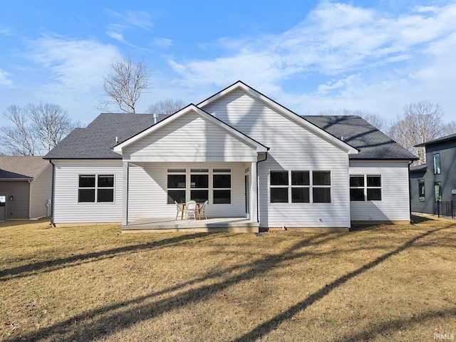 rear view of house with a yard and roof with shingles