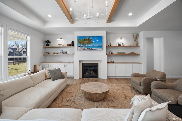 living area featuring a glass covered fireplace, beam ceiling, recessed lighting, and light wood-style floors