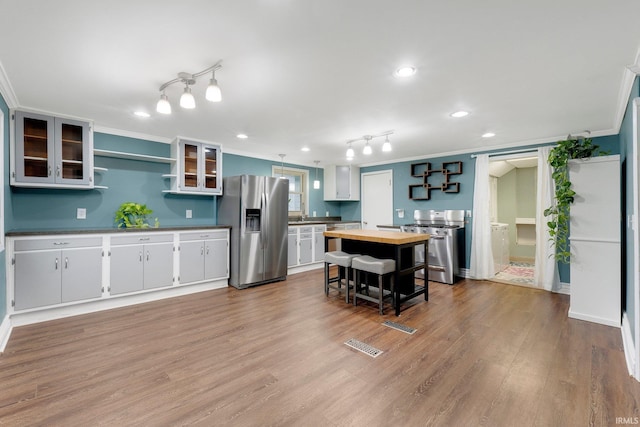 kitchen featuring open shelves, butcher block countertops, appliances with stainless steel finishes, and crown molding