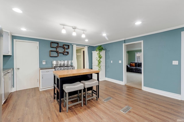 dining area with crown molding, light wood-style flooring, and visible vents