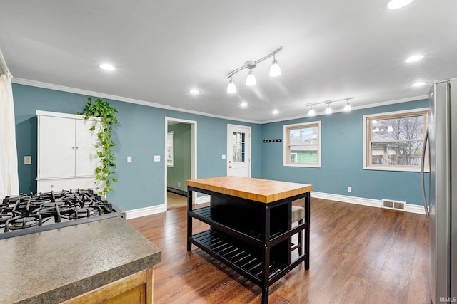 kitchen with visible vents, crown molding, baseboards, dark wood-style floors, and stainless steel appliances