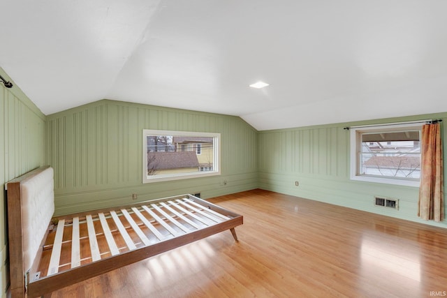 unfurnished bedroom with visible vents, wood finished floors, radiator heating unit, and vaulted ceiling