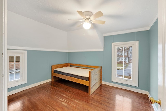 bedroom with a ceiling fan, baseboards, and wood-type flooring