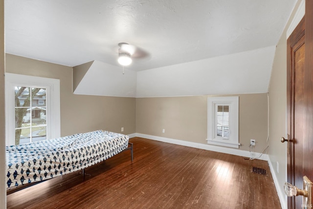 bedroom with vaulted ceiling, multiple windows, baseboards, and hardwood / wood-style flooring