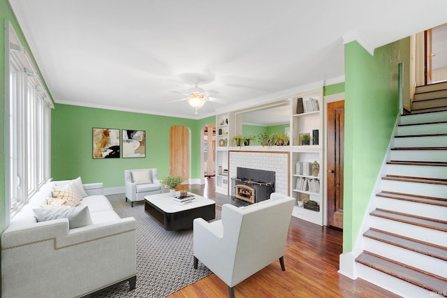 living room with stairway, wood finished floors, arched walkways, ceiling fan, and crown molding