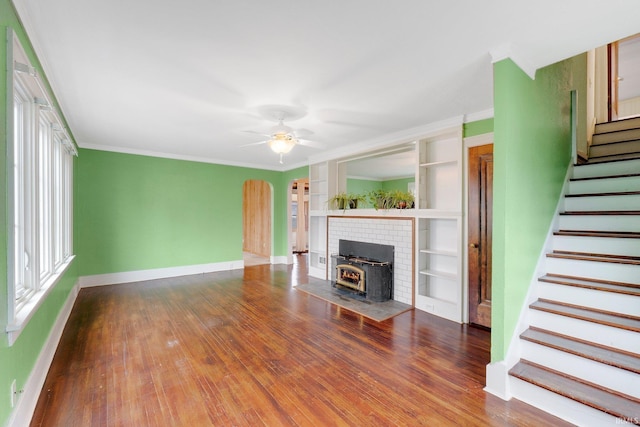 unfurnished living room featuring arched walkways, stairway, hardwood / wood-style flooring, and ornamental molding