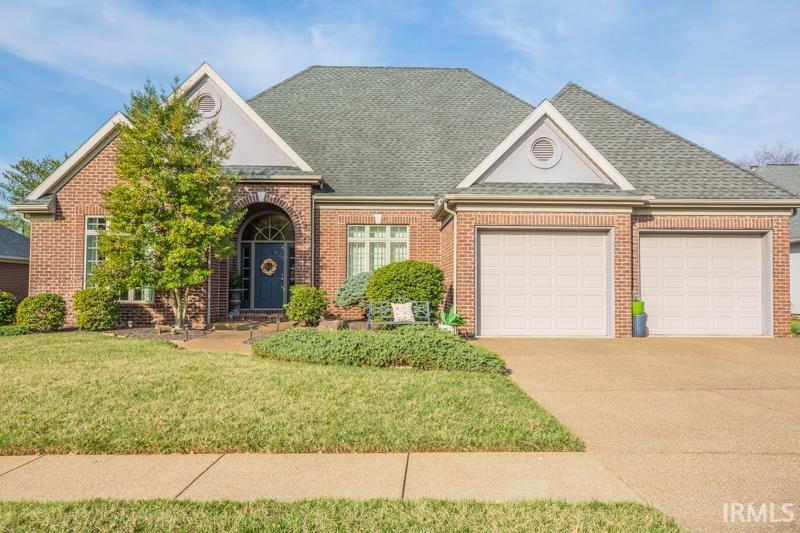 view of front of property with brick siding, a front yard, an attached garage, and driveway