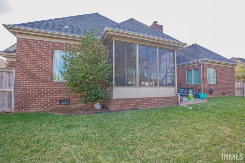 back of property with brick siding, a lawn, a chimney, a sunroom, and crawl space