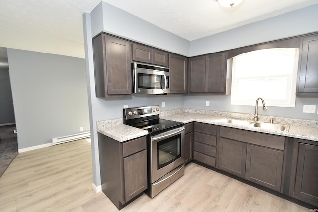 kitchen with dark brown cabinets, a baseboard heating unit, light countertops, stainless steel appliances, and a sink