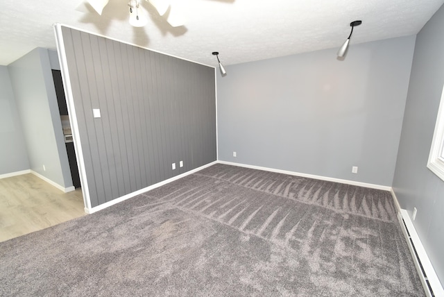 carpeted spare room with baseboards, baseboard heating, and a textured ceiling