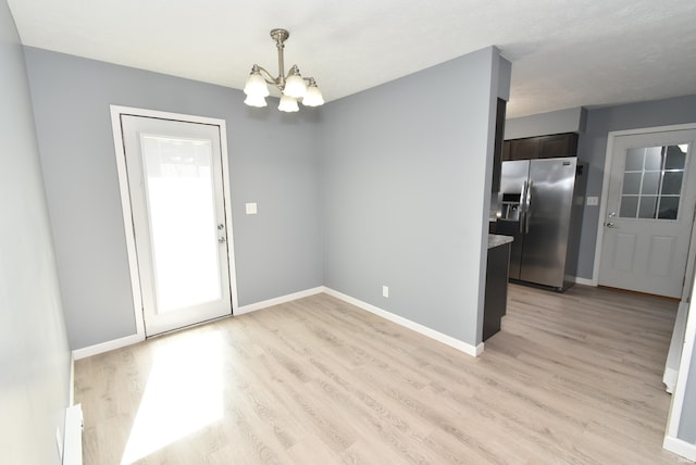 unfurnished dining area with an inviting chandelier, light wood-style floors, baseboards, and a wealth of natural light