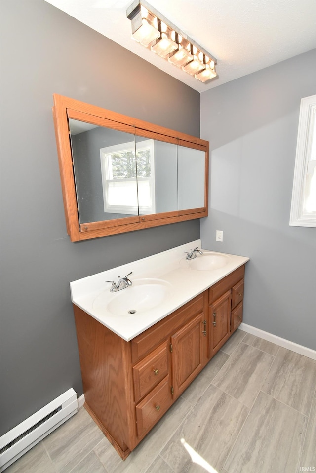 bathroom with double vanity, a baseboard heating unit, baseboards, and a sink