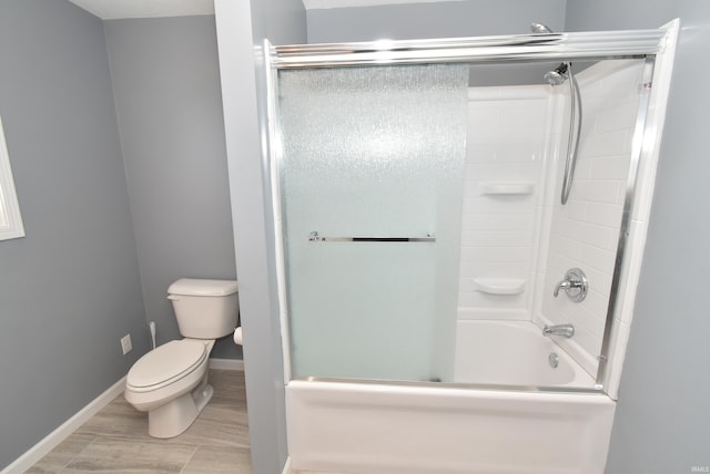 full bathroom with toilet, baseboards, and shower / bath combination with glass door