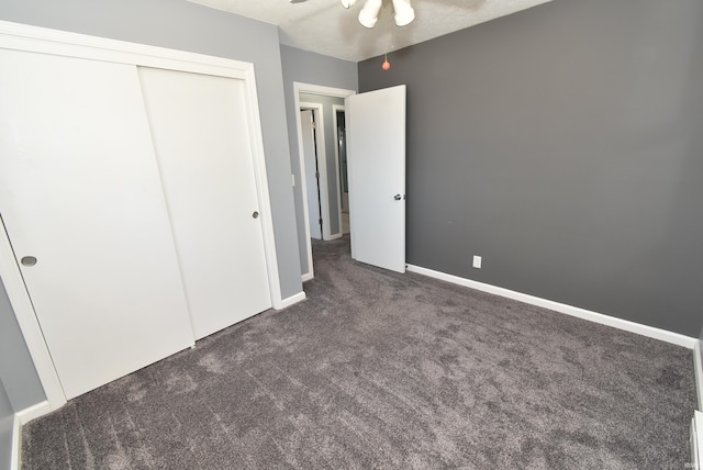 unfurnished bedroom with a closet, baseboards, and dark carpet