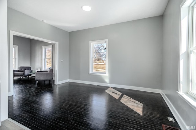 empty room with visible vents, wood finished floors, and baseboards