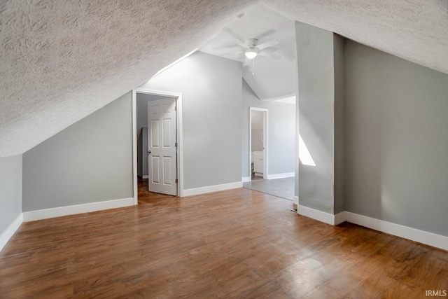 additional living space featuring ceiling fan, baseboards, a textured ceiling, and wood finished floors