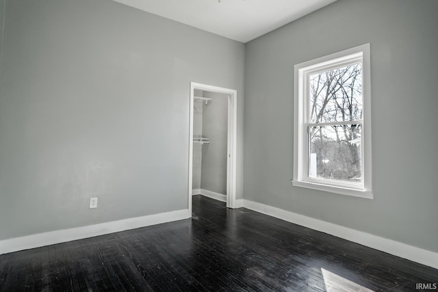 unfurnished bedroom with dark wood finished floors, a closet, and baseboards